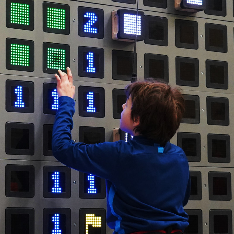 Dziecko wspinające się na interaktywnej ściance wspinaczkowej skywall